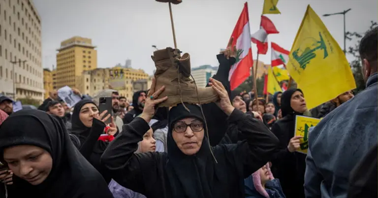 লেবাননের যোদ্ধাকে সম্মান জানানোর এক নারী মাথায় প্রতীকী বুট রাখেন